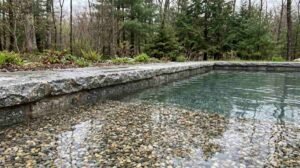 Close-up of a pebble aggregate pool finish in a New England backyard pool