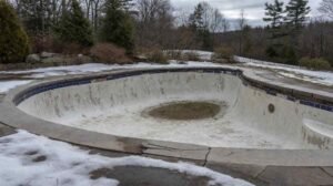 New Hampshire swimming pool after winter with cracked coping and popped waterline tile